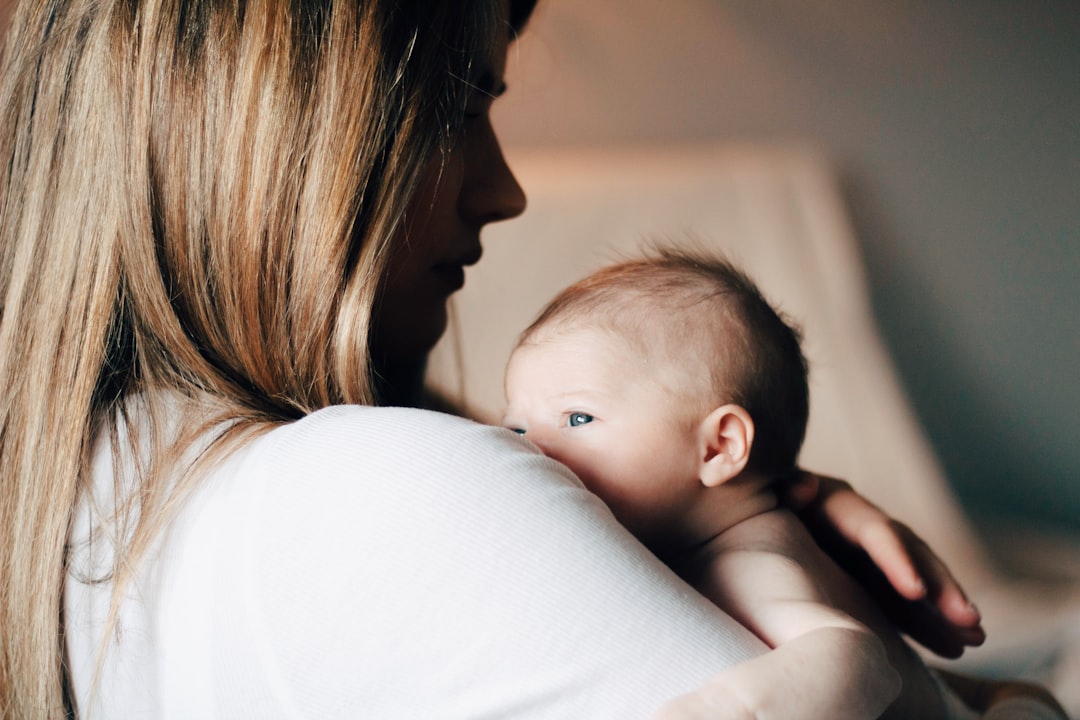 A parent holding a newborn against their shoulder in soft light